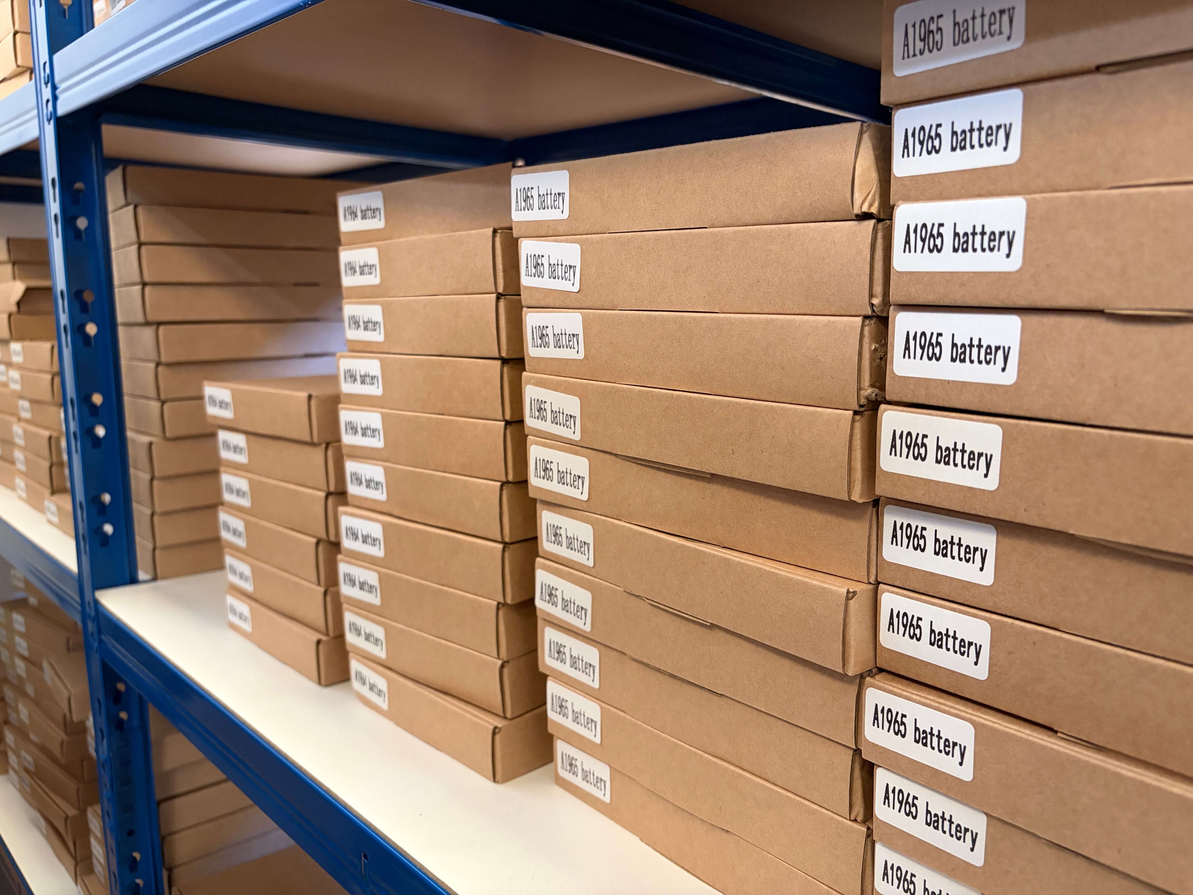 Stacks of new boxed MacBook batteries, parts kept in stock for repairs