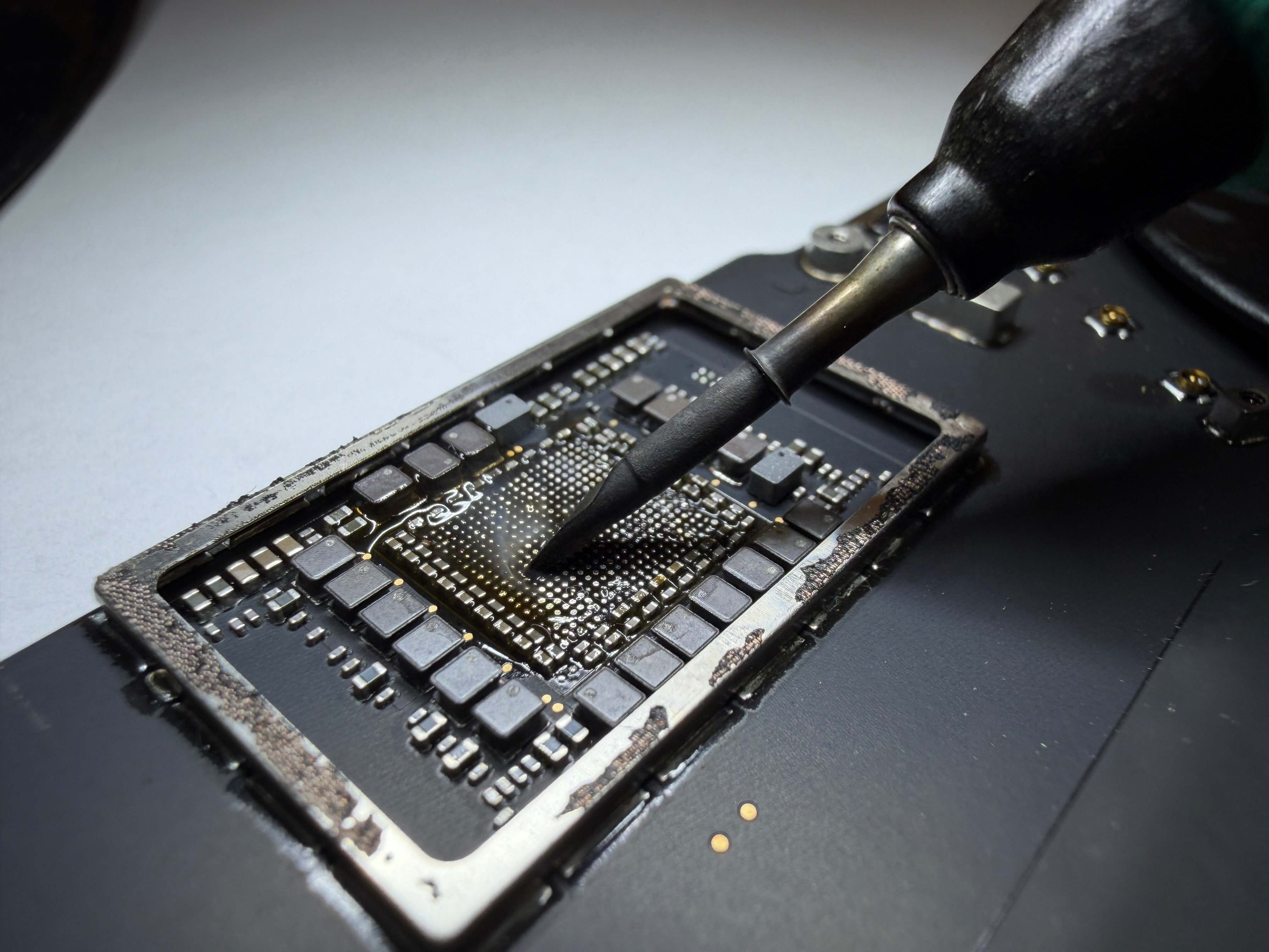 Close up of soldering iron tinning PMIC pads on MacBook Pro 14"